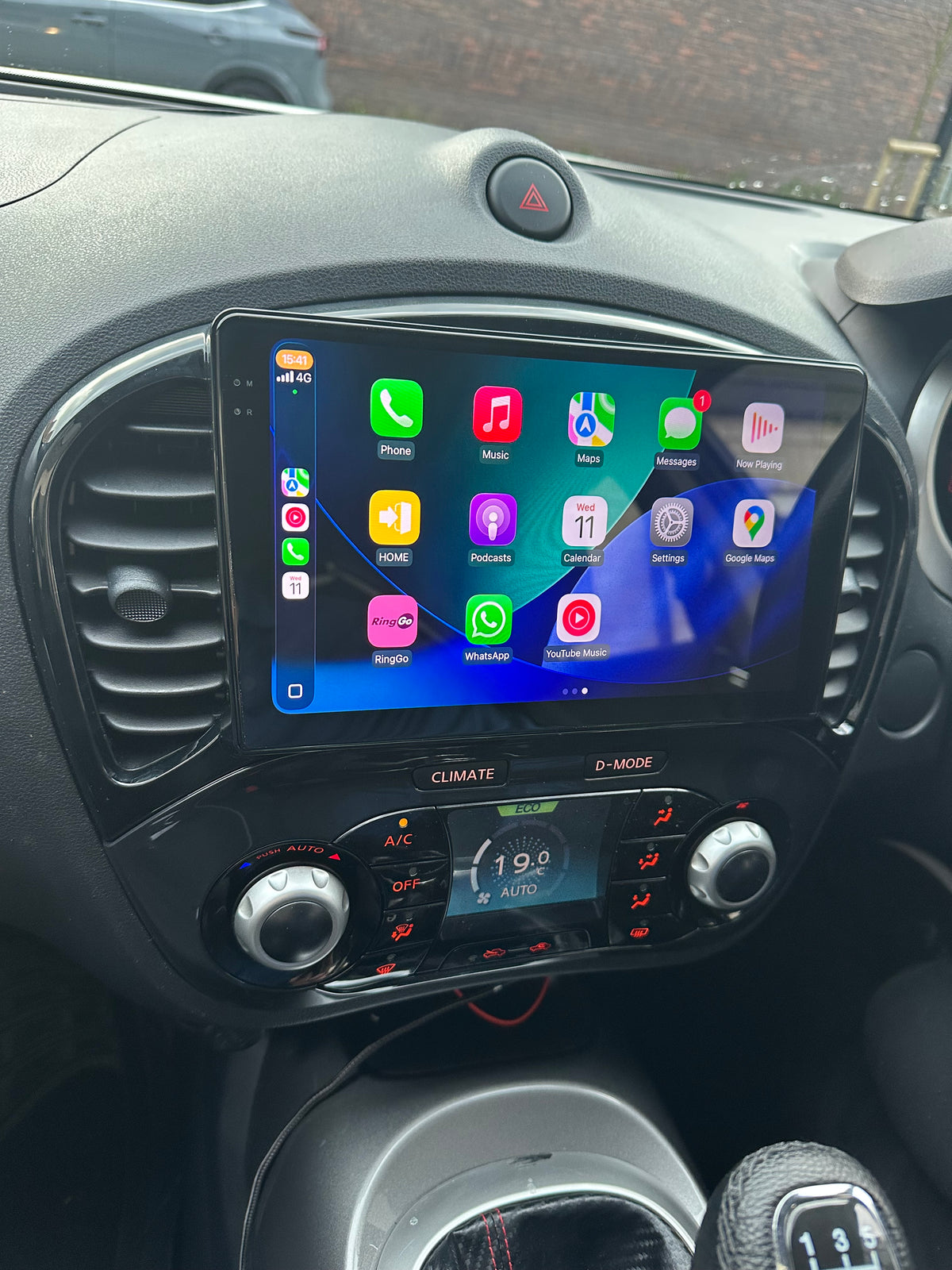 Nissan Juke 2010–2019 installed touchscreen showing Apple CarPlay apps above the climate controls.